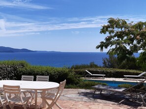 Eine Terrasse mit Pool, Liegestühlen und einem Tisch mit Stühlen.