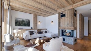 A modern living room with a fireplace, wooden ceiling beams, a sofa set, and a large painting on the wall. - Brand-new apartment in Lavachet, near slopes, sleeps 10 (Tignes)