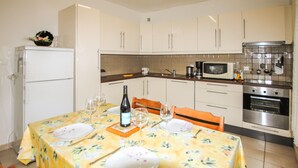 Una zona de comedor con una mesa lista para dos personas, un microondas y un refrigerador al fondo.