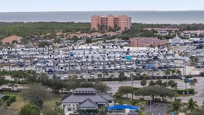 Ein Tennisplatzkomplex mit mehreren Plätzen, umgeben von einem Parkplatz und Blick auf ein Wohngebiet mit Gebäuden im Hintergrund.