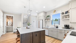 Una cocina moderna con una isla grande, armarios blancos y vistas al exterior.
