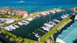 An aerial view of a marina with multiple boats docked, surrounded by buildings and greenery. - Oceanfront, Sapphire Beach, Pool, 2 bedrooms, 2 bath (St. Thomas)