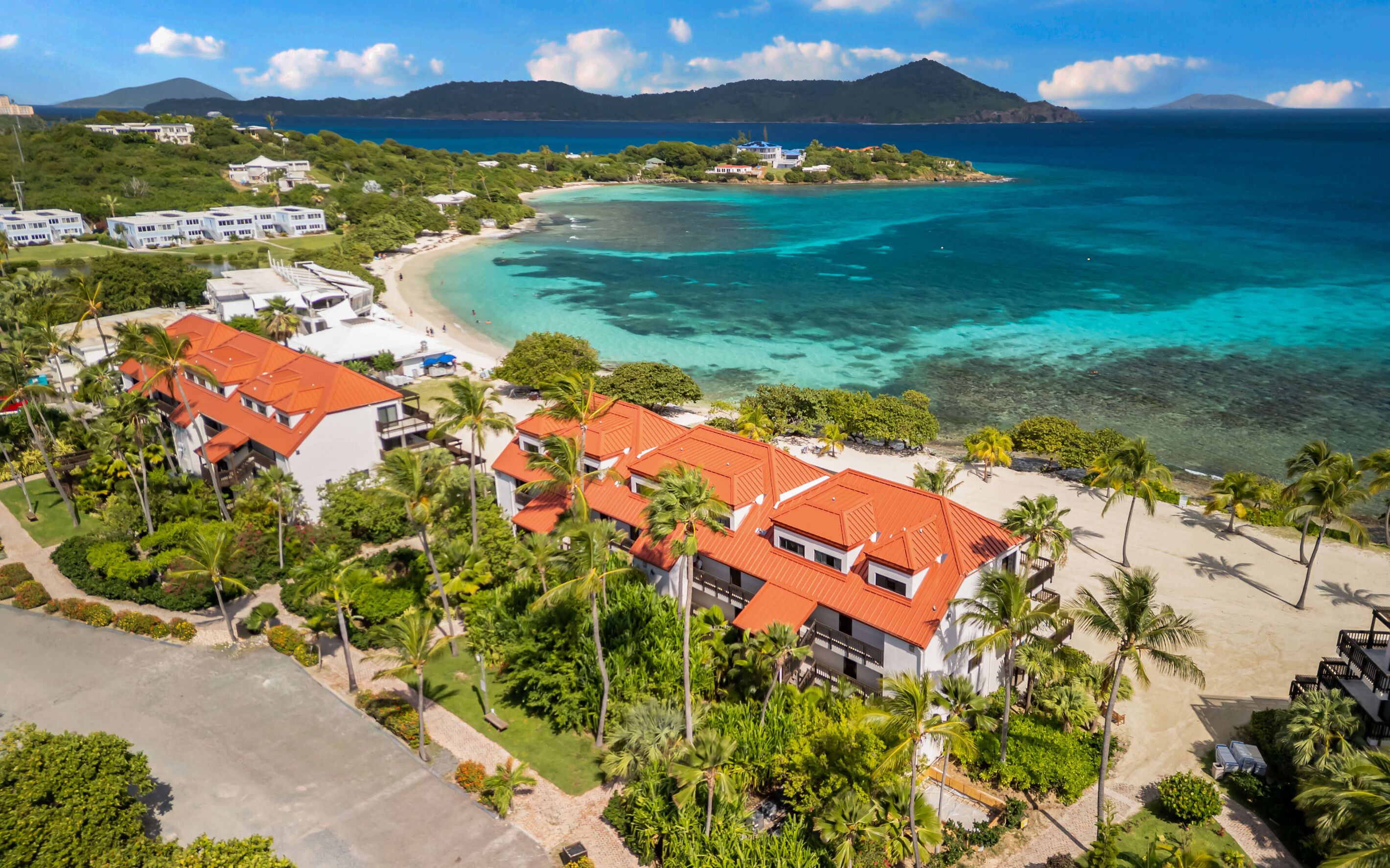 A resort with multiple buildings, a beach, and clear blue waters.