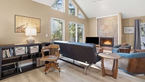 A spacious living room with a fireplace, comfortable seating, and a large window providing natural light. - Latitude 45 - forest retreat near Manzanita beach (Manzanita)