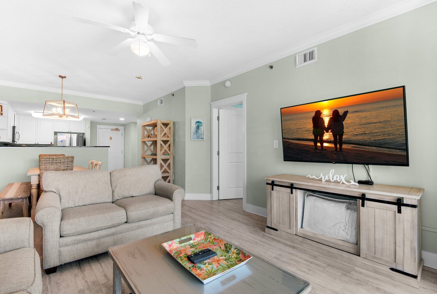 A living room with a sofa, coffee table, and a TV displaying a sunset scene.