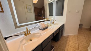 A bathroom with two sinks, a large mirror, and a towel rack. - Your Arlington Hotspot: Games, Flights & Family Fun (Arlington)