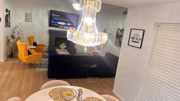 A modern living room with a TV, chandelier, and dining area. - Your Arlington Hotspot: Games, Flights & Family Fun (Arlington)