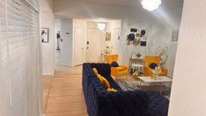 A modern living room with a dark blue sofa, yellow armchairs, and a small round table. - Your Arlington Hotspot: Games, Flights & Family Fun (Arlington)