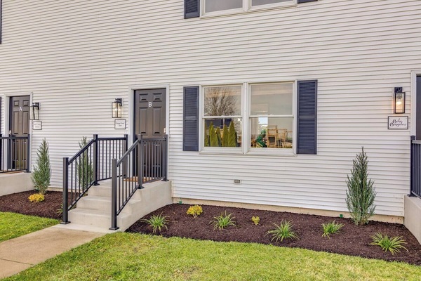 Entryway w/ steps, railing & landscaped walkway leading up to the door