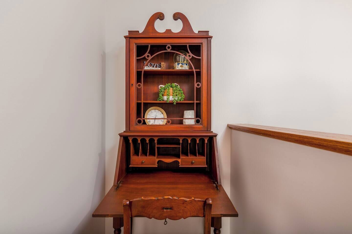 Een houten bureau met een klok en een plank met decoratieve spullen.