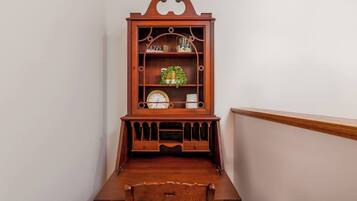Een houten bureau met een klok en een plank met decoratieve spullen.