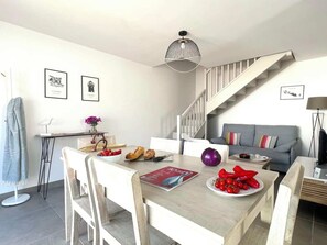 A modern living space with a dining area, a staircase, and a sofa. - Villa No. 7 - Les Sauzes   (La Flotte)
