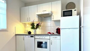 Eine moderne Küche mit weißen Schränken, einem Einbauofen, einer Mikrowelle und einem Kühlschrank.