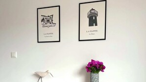 Un bureau blanc orné d’un vase de fleurs et d’une sculpture d’oiseau, avec de part et d’autre deux tableaux encadrés accrochés au mur.