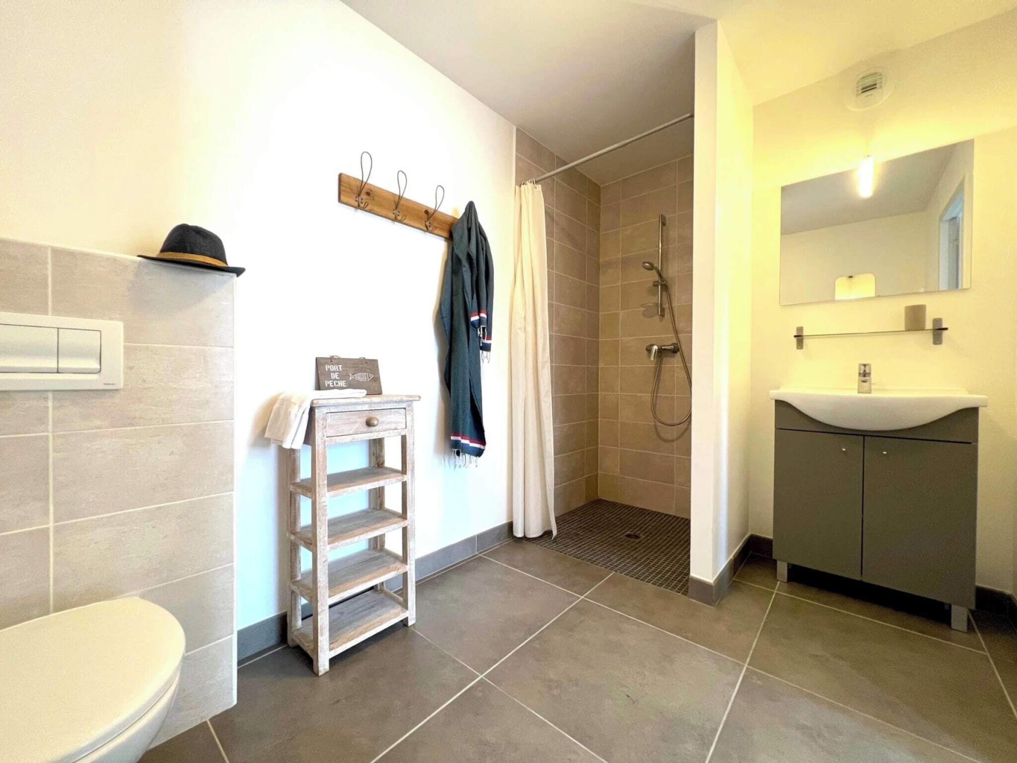 A bathroom with a toilet, a sink, a shower, and a towel rack.