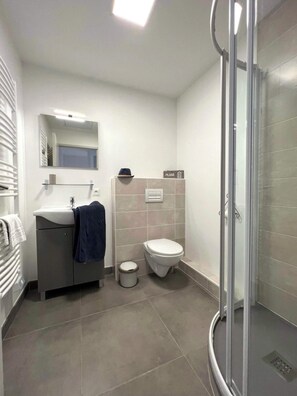 Et moderne badeværelse med bruser, toilet og vask.
