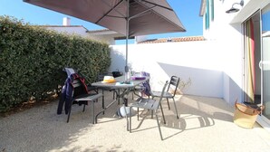 Un patio con una mesa, sillas, un paraguas grande y una cesta.