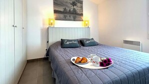 Un dormitorio con cama, dos lámparas de noche, un cuadro en la pared y una bandeja con croissants y una taza.