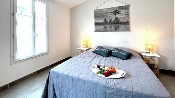 A bedroom with a bed, a window, a wall-mounted picture, bedside lamps, and a tray with food and drinks. - Villa n°6 - The Target (La Flotte)