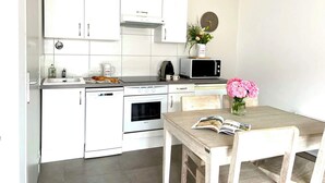A modern kitchen with white cabinets, a microwave, a coffee maker, and a dining table with chairs. - Villa n°6 - The Target (La Flotte)
