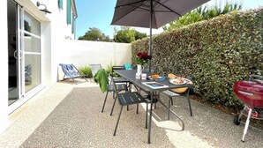 A patio with a table, chairs, a grill, and a large umbrella. - Villa n°5 - Les gollandières (La Flotte)