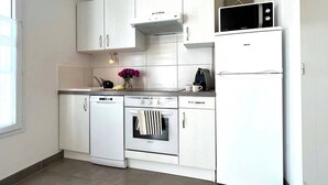 A compact kitchen with white cabinetry, a built-in oven, a microwave, and a dishwasher. - Villa n°5 - Les gollandières (La Flotte)