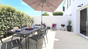 An outdoor patio with a table, chairs, a large umbrella, and a grill. - Villa n°9 - Le martray (La Flotte)