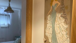 Un dormitorio con una cama, una lámpara colgante y un cartel de una mujer con un vestido frente a la Torre Eiffel.