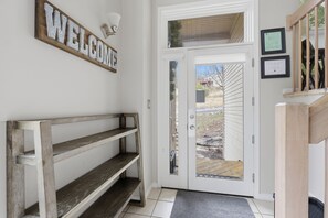 Eine Holzbank, ein Willkommensschild, eine Glastür und zwei gerahmte Zertifikate an der Wand.