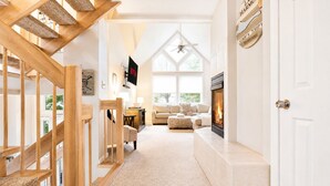 Ein modernes Interieur mit einer Holztreppe, einem Kamin, einer Couch und einem Fernseher.