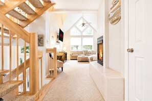 Ein modernes Interieur mit einer Holztreppe, einem Kamin, einer Couch und einem Fernseher.