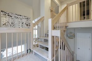 A multi-level interior with a staircase, a large wall art piece, and a door with a sign. - Mystic  Retreat | Hot Tub & Lake Harmony Access (Lake Harmony)