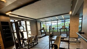A modern gym with exercise equipment, a treadmill, and a weight bench. - Flat Quality Comfort CoHouse - Tambaú (João Pessoa)
