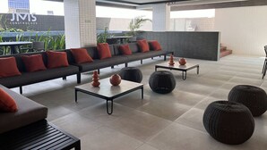 A modern lounge area with a sofa, coffee tables, and decorative vases. - Flat Quality Comfort CoHouse - Tambaú (João Pessoa)