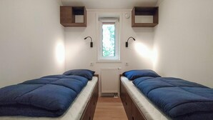 Una habitación pequeña con dos camas, una ventana y un radiador.