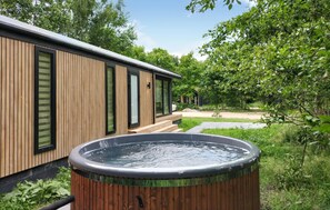 A modern wooden building with large windows and a hot tub in the foreground. - Sernets Recreatie Chalet 111 (Oud Gastel)