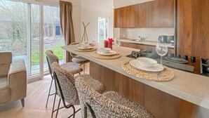 Una cocina moderna con una isla grande, taburetes de bar y vistas al jardín.