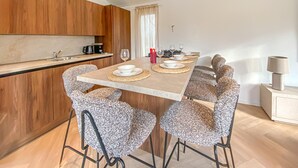 Una cocina moderna con armarios de madera, una mesa de comedor con platos y vasos blancos, y una vela sobre la mesa.