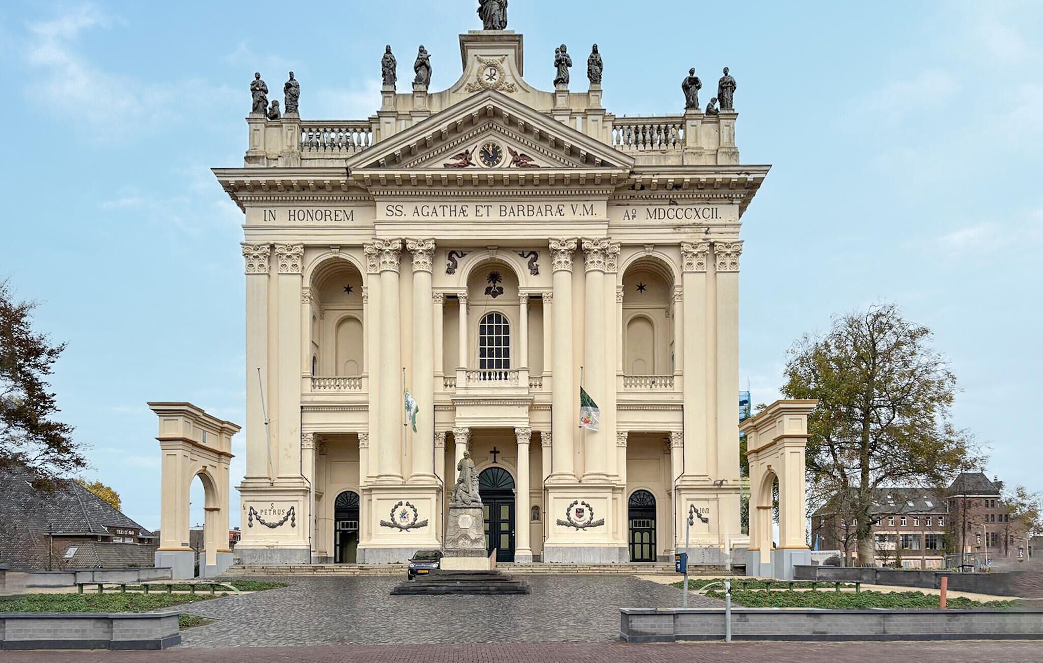 Un imposant bâtiment historique à l’architecture classique, doté d’une entrée centrale, de statues et de décorations raffinées.