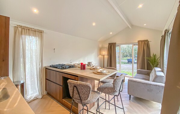 Een moderne keuken met een centraal eiland, barkrukken en een eettafel gedekt voor vier personen.