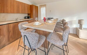 Een moderne keuken met houten kastjes, een eettafel voor vier met geweven placematen en een rode kaars op de tafel.