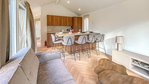 Un salon moderne comprenant un canapé, une table basse et un coin bar avec des tabourets.