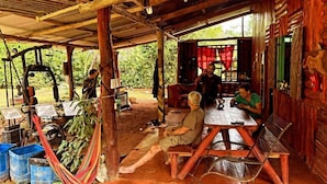 A rustic wooden structure with a covered outdoor seating area, a hammock, and a table with chairs. - Ceiba Ganadito (Drake Bay)