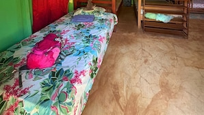 A room with bunk beds, a bed with a floral bedspread, and green walls. - Ceiba Ganadito (Drake Bay)