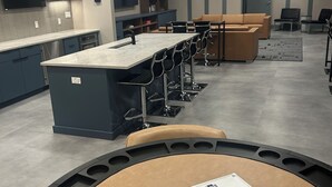 Una cucina moderna con isola centrale, sgabelli da bar e zona pranzo con divano e sedie.