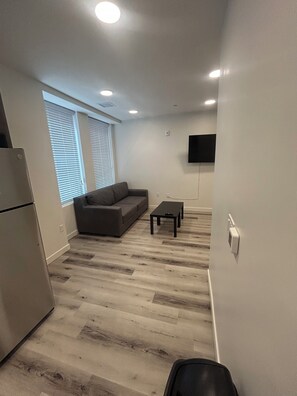 A modern living room with a grey sofa, a small black table, and a flat-screen TV mounted on the wall. - Salt Lake City Luxury Loft 214 Downtown (Salt Lake City)