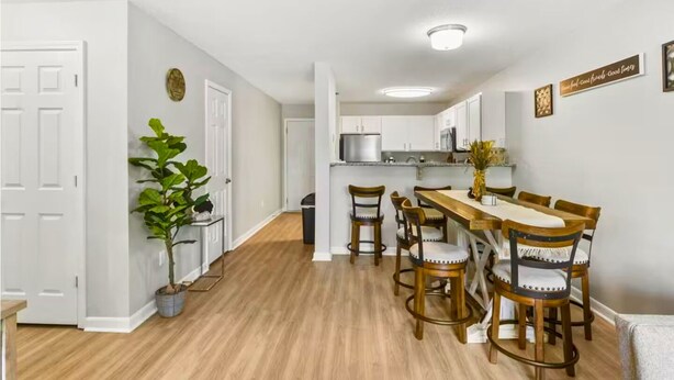 Una cocina moderna con armarios blancos, una mesa de comedor de madera y una planta en maceta.
