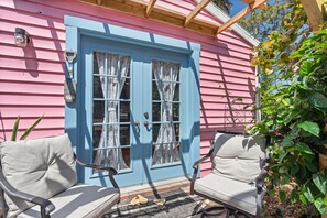 A pink house with a blue door, two chairs outside, and a wooden porch. - Charming Nokomis Bungalow • 1 Bedroom • Minutes to the Beach• AC & Laundry (Nokomis)