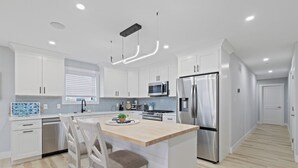 Une cuisine moderne avec des armoires blanches, des appareils en acier inoxydable et un îlot central en bois.