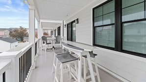 Un balcon fermé avec des balustrades blanches, une table avec des chaises et de grandes fenêtres.